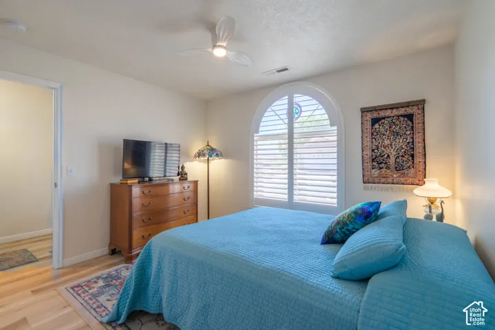 Arched window with plantation shutters, ceiling fan, wood-finish flooring, and recessed lighting
