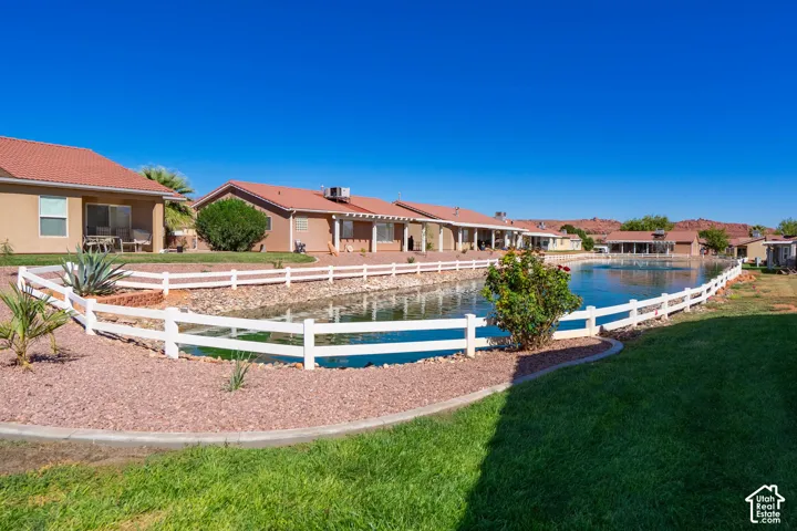Expansive outdoor area featuring a water feature, white perimeter fencing, manicured green lawn, and decorative rock landscaping