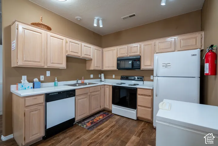 Kitchen featuring wood-finish flooring, light-toned cabinetry, white countertops, built-in microwave, and stainless steel sink