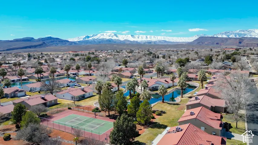 Community with red tile roofs, multiple ponds, tennis court, and desert landscape