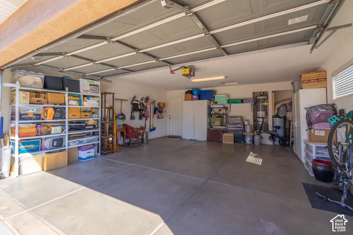 Spacious garage with sectional overhead door, concrete flooring, and ample lighting