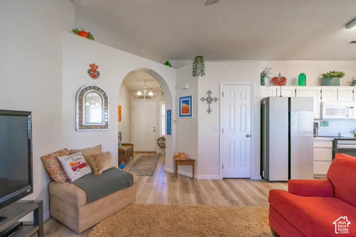 Archway entry, light-tone wood-finish flooring, white paneled doors, white cabinetry, and stainless steel appliances