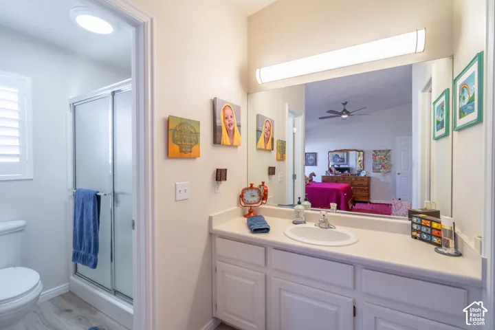 Bathroom featuring a single vanity with an integrated sink, a large wall-mounted mirror, white cabinetry, and a shower enclosure with a sliding glass door