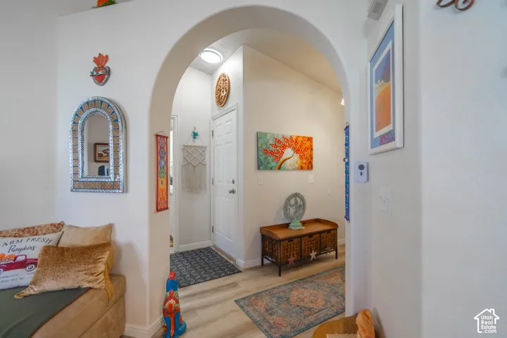 Arched entryway featuring light-toned walls and wood-finish flooring