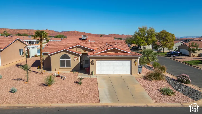 Stucco exterior with a tile roof, arched window, attached garage, and a concrete driveway