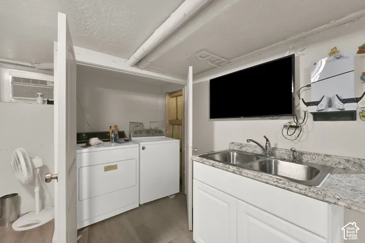Efficient kitchen layout featuring white cabinetry, stainless steel dual-basin sink with granite-style countertop, and integrated wall-mounted flat-screen display