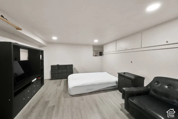 Spacious bedroom with wood-finish flooring, recessed ceiling lighting, and ample built-in storage cabinetry