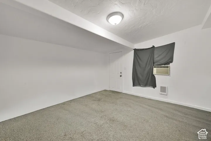 Spacious carpeted bedroom with neutral wall finishes, recessed ceiling lighting, and a window with blackout treatment