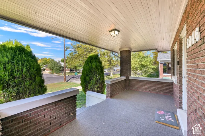 Covered front porch featuring brick half-walls, a painted wood-plank ceiling, and a flush-mount light fixture