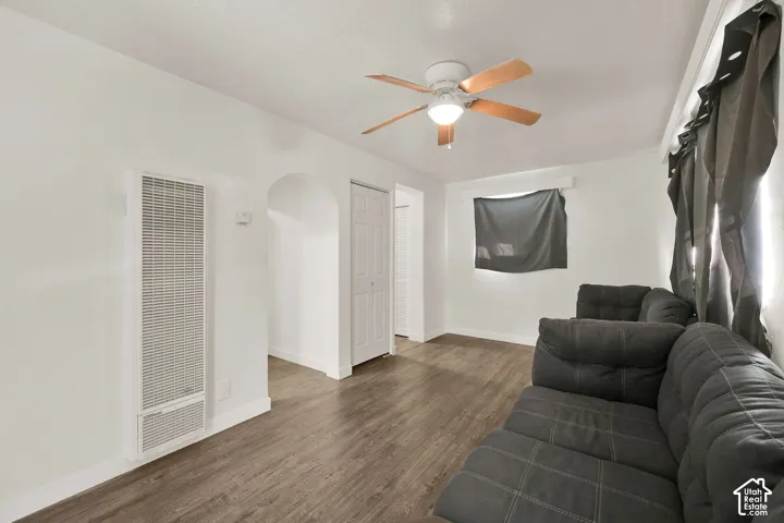 Spacious bedroom featuring wood-finish flooring, ceiling fan with integrated lighting, and multiple closet doors for storage