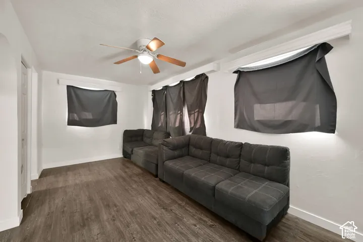 Spacious recreation room featuring wood-finish flooring, ceiling fan with integrated lighting, and white painted walls