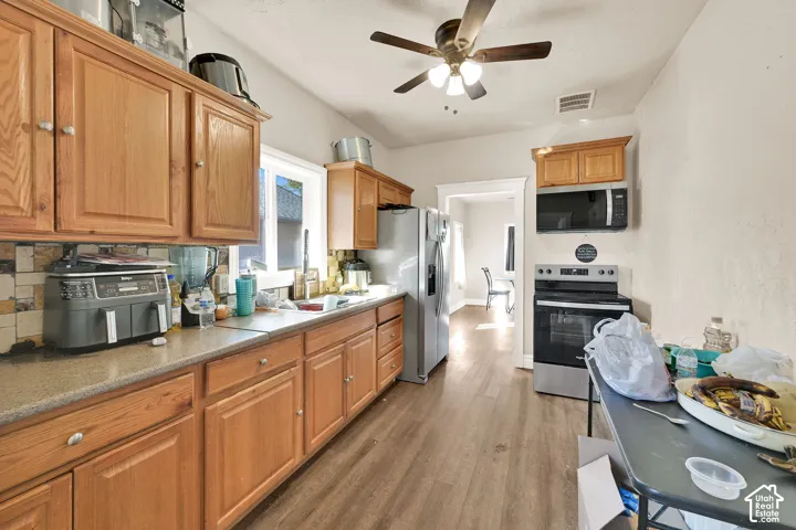 Kitchen featuring wood cabinetry, stone-finish countertops, wood-finish flooring, and a stainless steel range with an overhead microwave