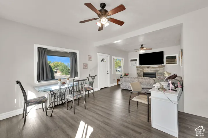 Open-concept living area featuring dark wood-finish flooring, ceiling fan with integrated lighting, and abundant natural light from multiple windows