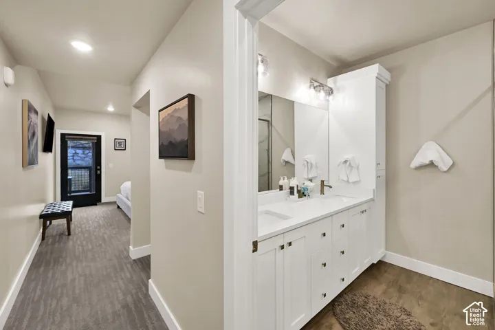 Double vanity with integrated sinks, white cabinetry, chrome fixtures, and a tall linen cabinet