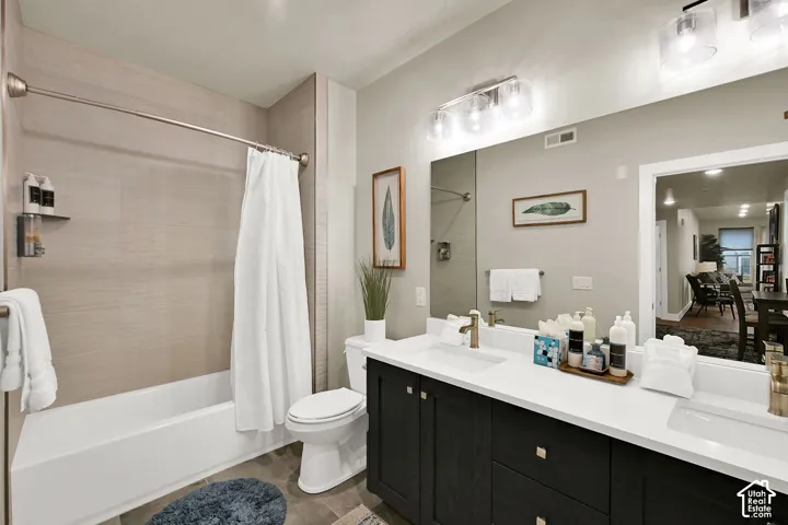 Dual sink vanity with dark wood-finish cabinetry, white countertops, and gold-tone fixtures