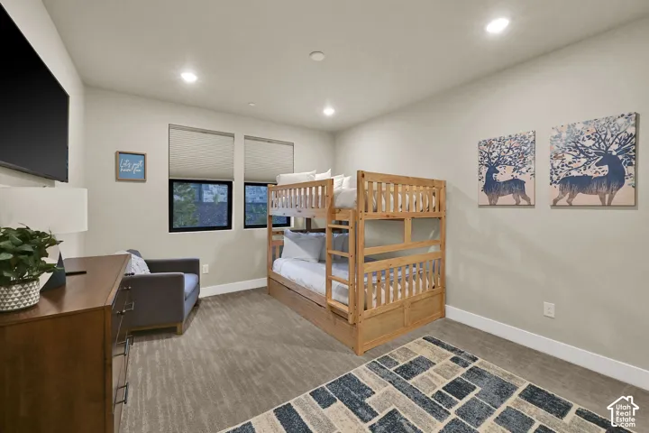 Recessed lighting, two windows with roller shades, light-toned walls, and carpet flooring