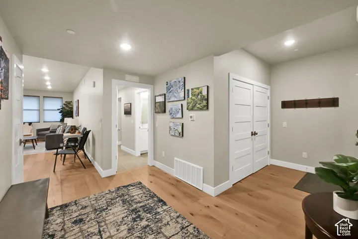 Welcoming foyer with warm wood-finish flooring, recessed ceiling lighting, and white six-panel closet doors