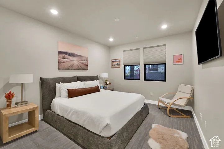 Recessed ceiling lighting, two windows with roller blinds, and wall-mounted television
