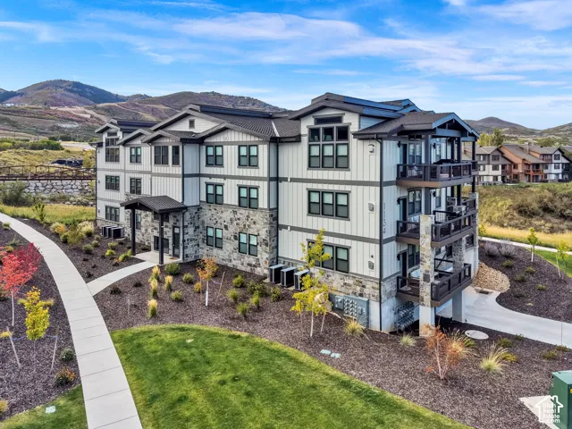 Multi-story building featuring stacked balconies, stone veneer accents, and dark-framed windows