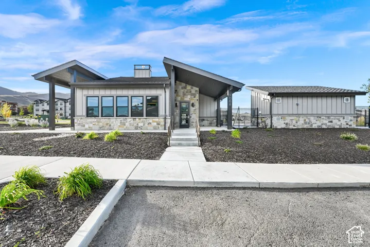 Modern exterior featuring vertical siding, stone accents, multiple large windows, and a covered entry