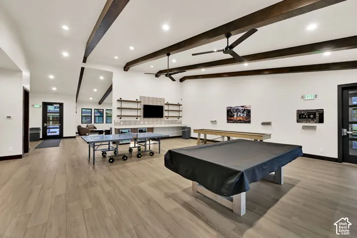 Vaulted ceiling with exposed wood beams, wood-finish flooring, recessed lighting, and built-in shelving