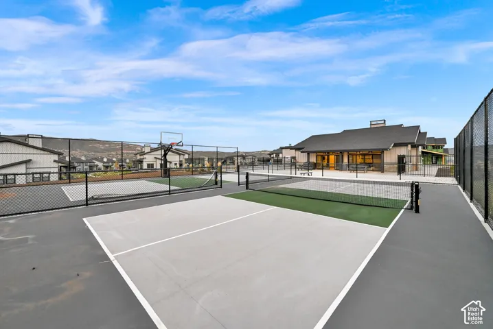Outdoor recreational area featuring multiple courts, a basketball hoop, and a community building with an outdoor patio