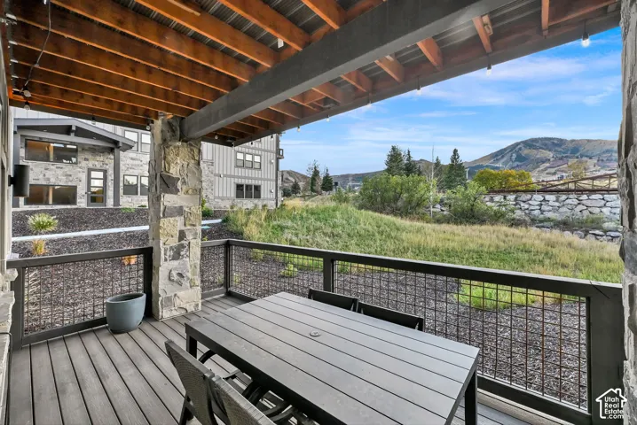 Covered outdoor deck with composite decking, stone pillar, and metal grid railing