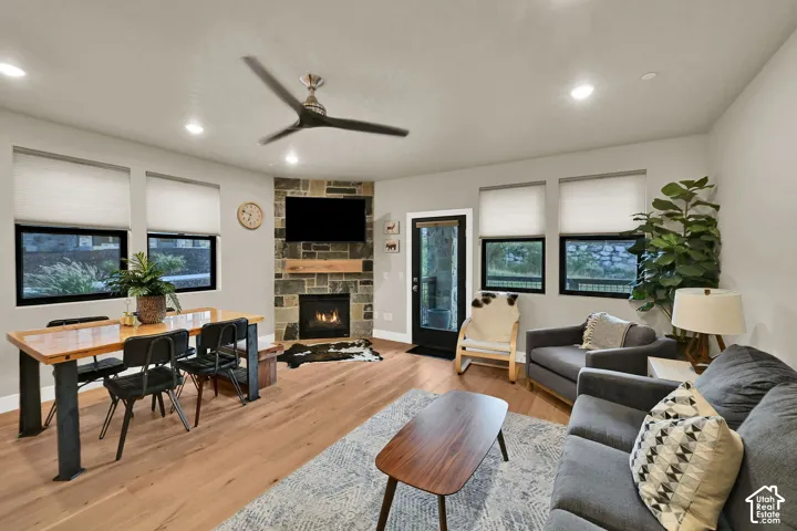 Hardwood-finish flooring, recessed lighting, and stone-accented fireplace with wood mantel