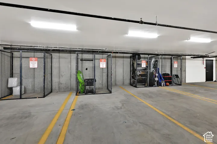 Assigned storage units with wire mesh construction, concrete walls, and overhead fluorescent lighting