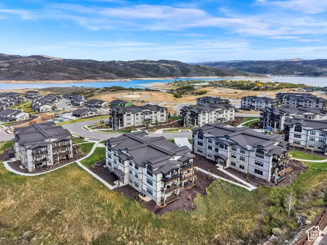 Modern multi-story apartment buildings with dark roofs, surrounded by landscaped grounds and paved pathways