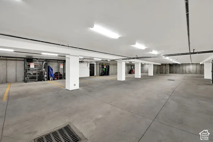 Garage with concrete flooring, exposed concrete walls, and overhead fluorescent lighting