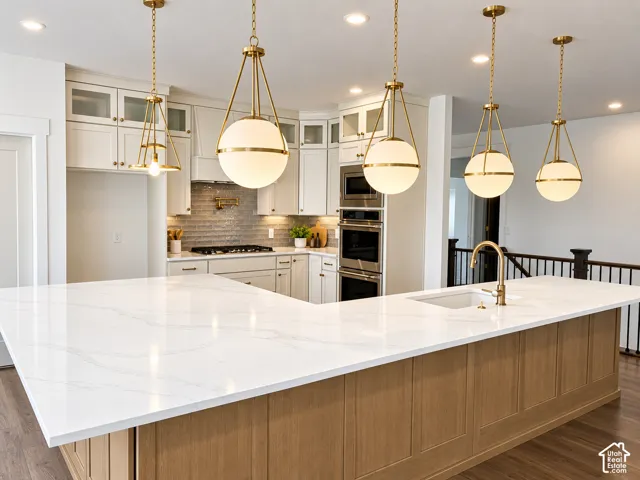 Spacious kitchen island with an undermount sink and a brass-finish faucet, featuring a white countertop and wood paneling