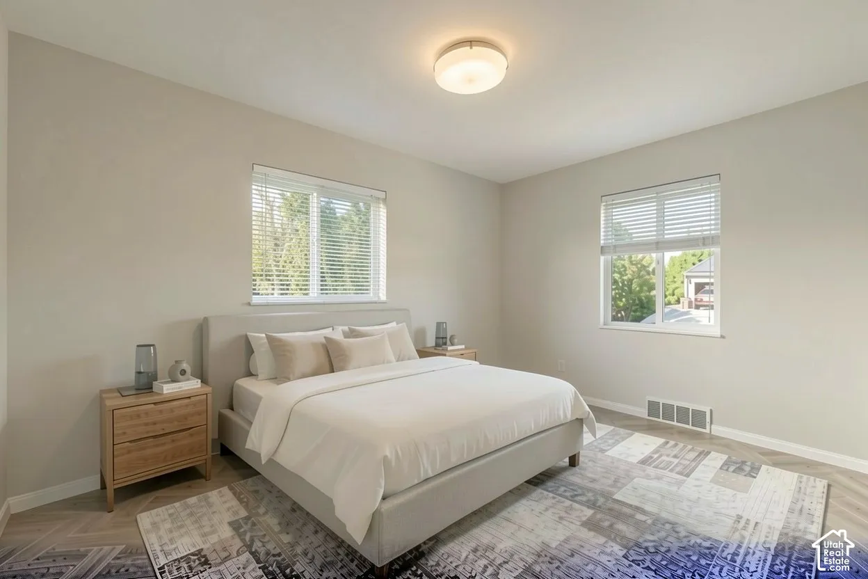 Light-filled room featuring two windows with blinds, a flush mount ceiling light fixture, and wood-finish flooring