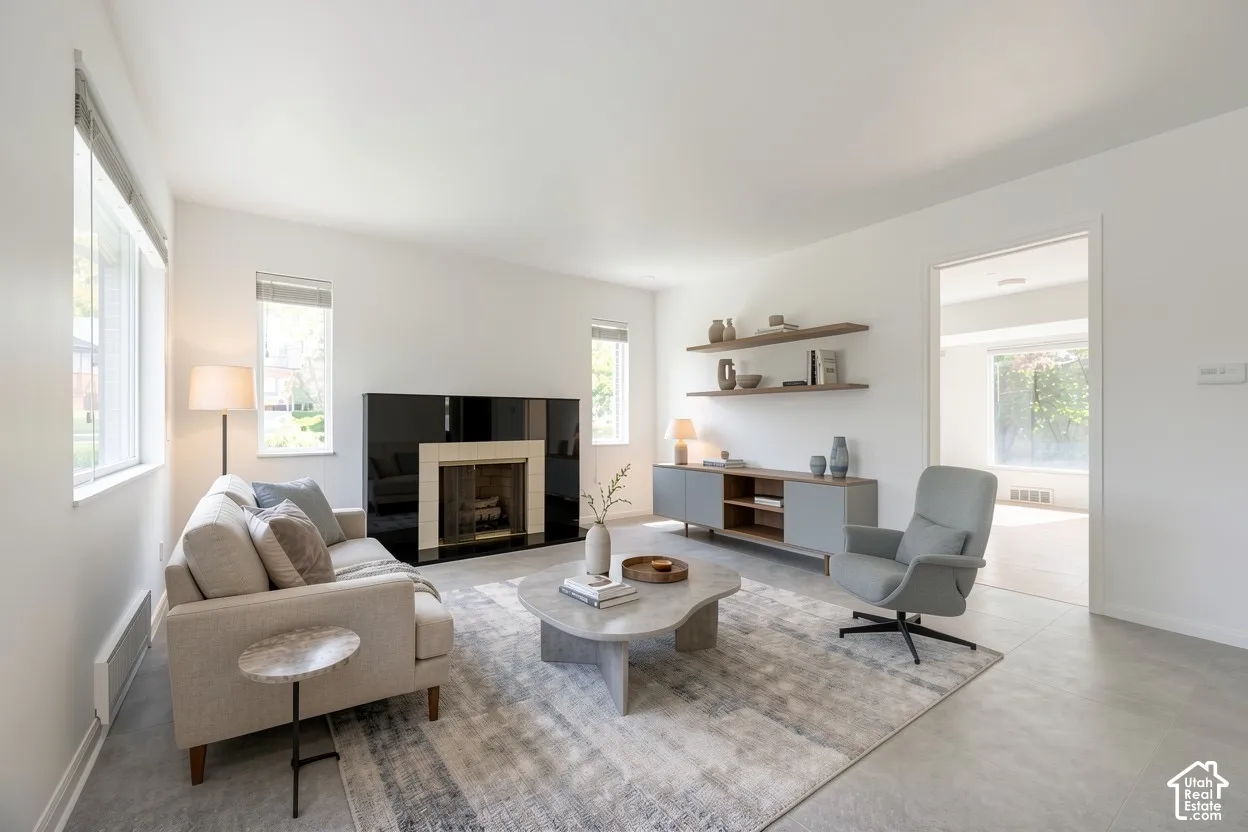 Fireplace with black surround and light-colored mantel, multiple windows, built-in shelving, and light-toned flooring