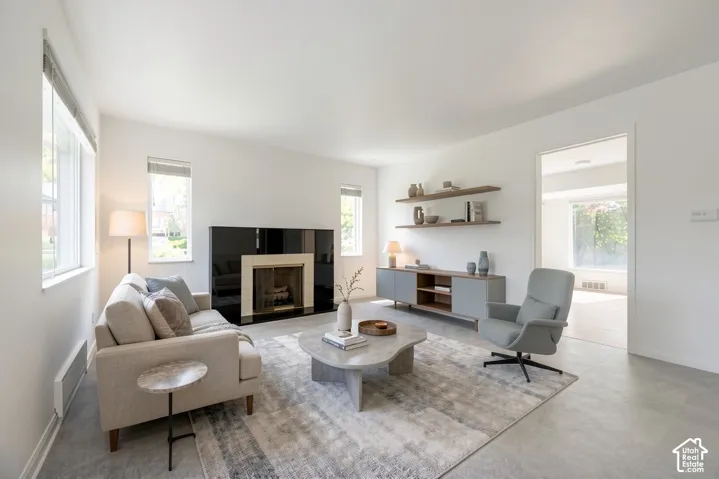 Fireplace with black surround and light-colored mantel, multiple windows, built-in shelving, and light-toned flooring