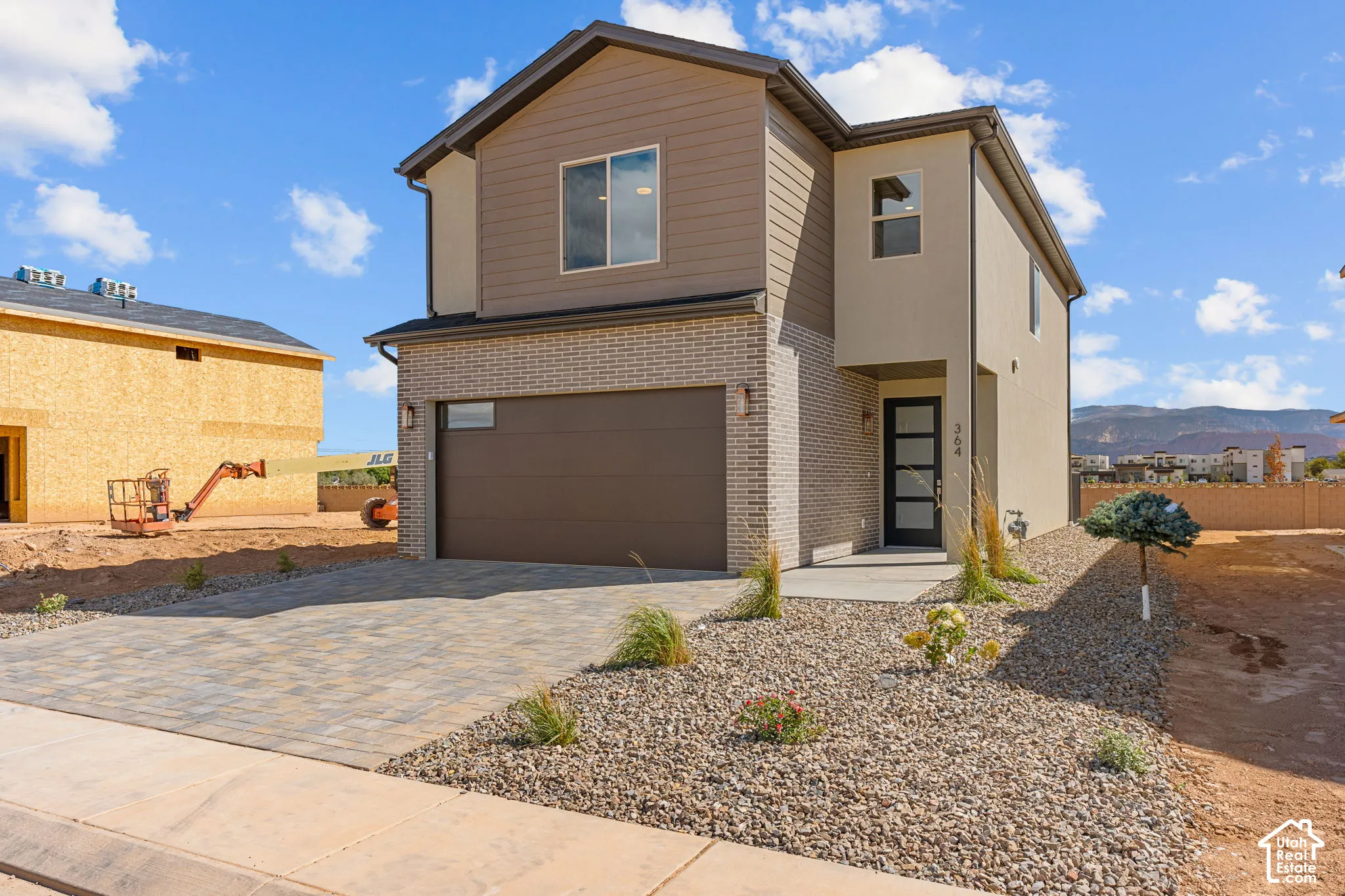 Modern two-story residence featuring a striking mixed-material exterior of taupe siding and brick detailing
