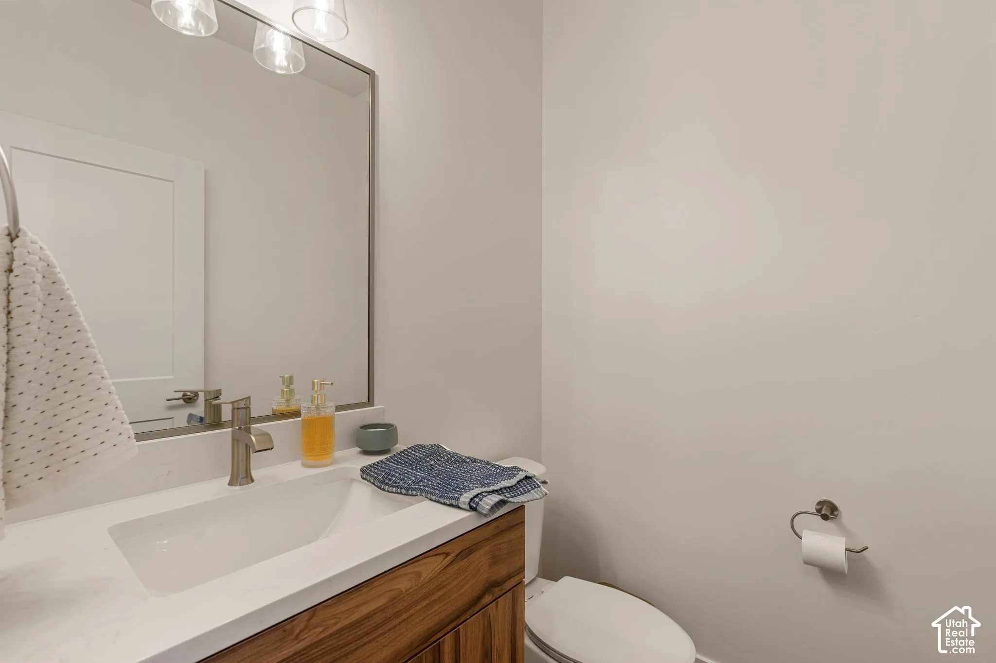 Solid surface countertop with integrated rectangular sink, single-handle faucet, wood-finish vanity, and wall-mounted mirror
