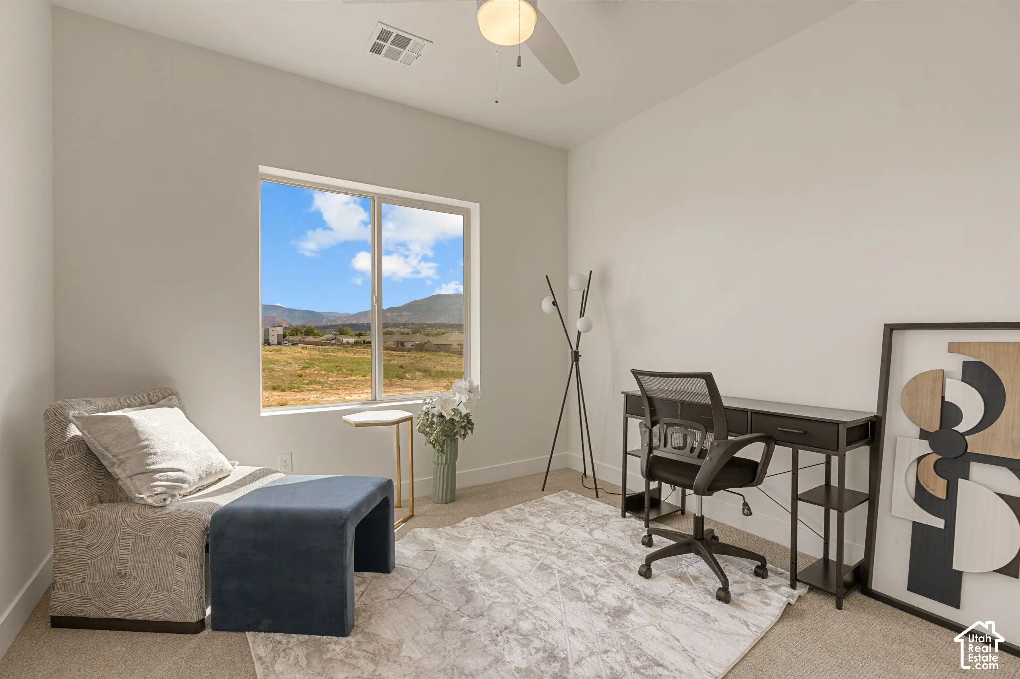 Bright, naturally lit office space featuring expansive windows framing scenic mountain and valley vistas, neutral wall finishes, light-toned area rug, and ample room for workspace configuration