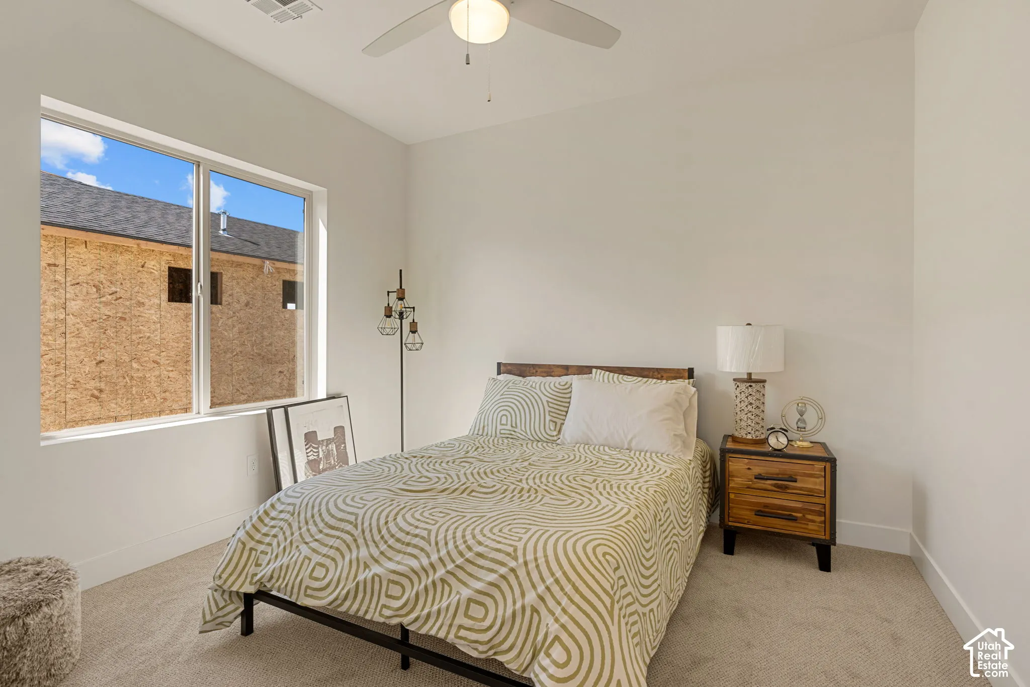 Bright secondary bedroom featuring large windows with natural light, neutral wall finishes, and polished concrete flooring