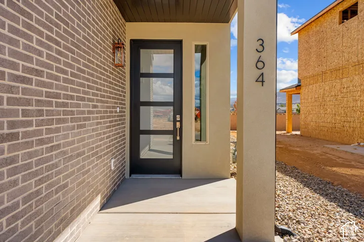 Modern entry featuring a black-framed glass door with multiple panes, cream-colored pilaster detailing, and house numbers displayed on the facade