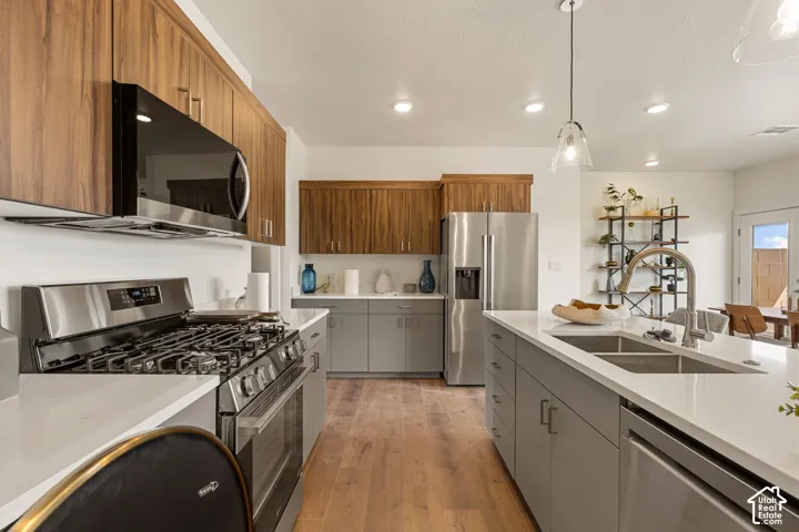 Chef's kitchen featuring stainless steel appliances, including a gas range and French-door refrigerator, paired with quartz countertops and a waterfall-edge island