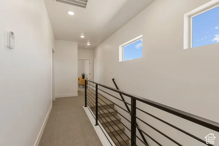 Upper-level landing featuring recessed lighting, two horizontal windows, and a black metal stair railing