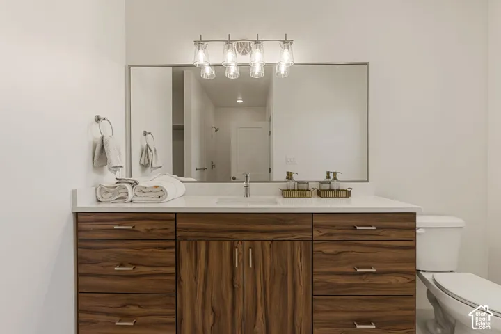 Spa-inspired primary bathroom vanity featuring rich wood cabinetry with multiple storage drawers, a white quartz countertop, and a wide framed mirror