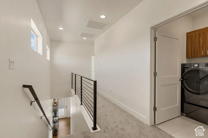 Modern laundry room featuring tile flooring, recessed ceiling lighting, and a front-load washer and dryer set