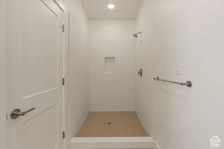 Spa-inspired walk-in shower featuring frameless glass enclosure, dual showerheads with brushed nickel fixtures, built-in niche storage, and textured tile flooring with integrated drainage