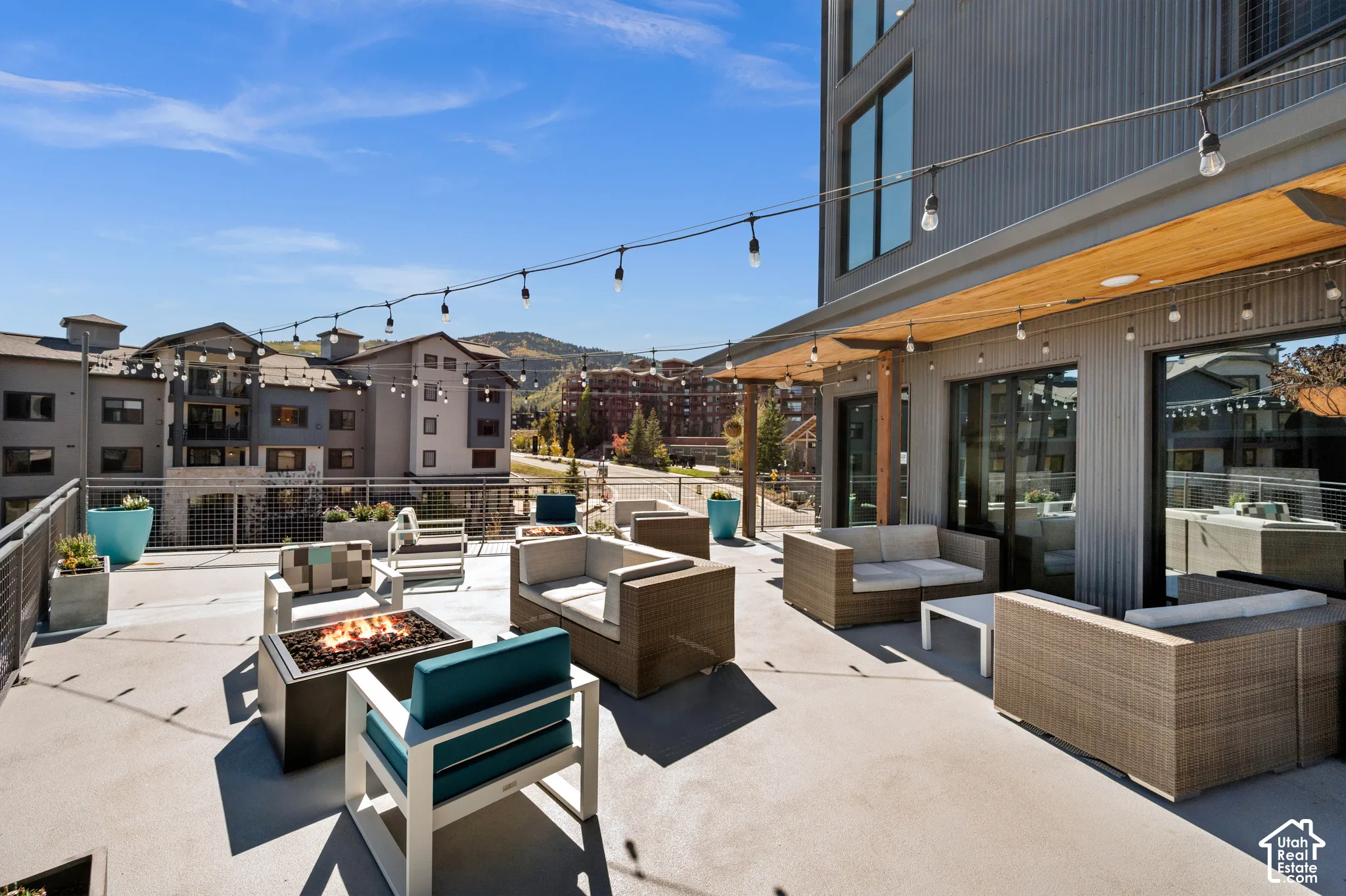 Expansive outdoor patio with a built-in fire pit, string lighting, and direct exterior access