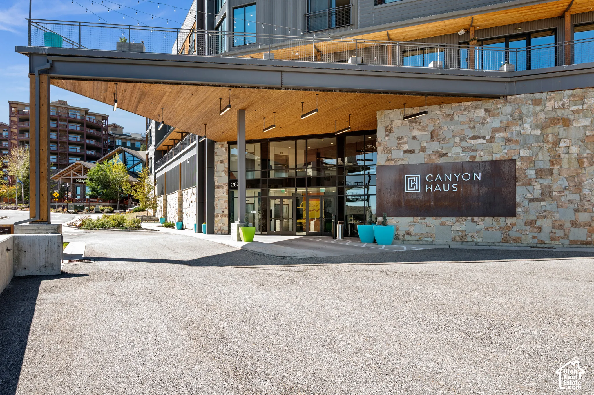 Building entrance featuring a stone facade, wood-finish overhang, and large glass doors