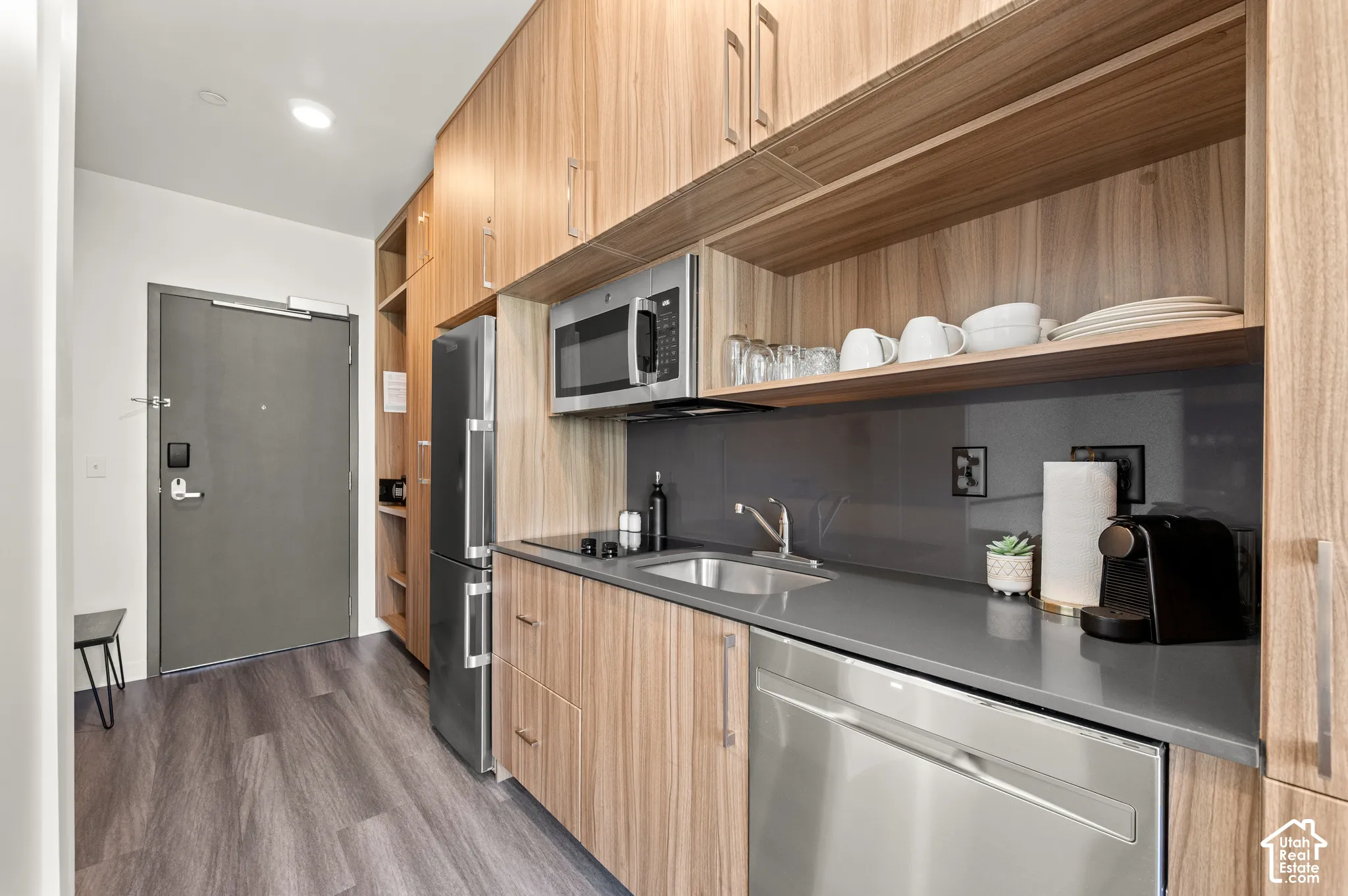 Compact kitchen featuring wood-finish cabinetry, stainless steel appliances, and a solid surface countertop