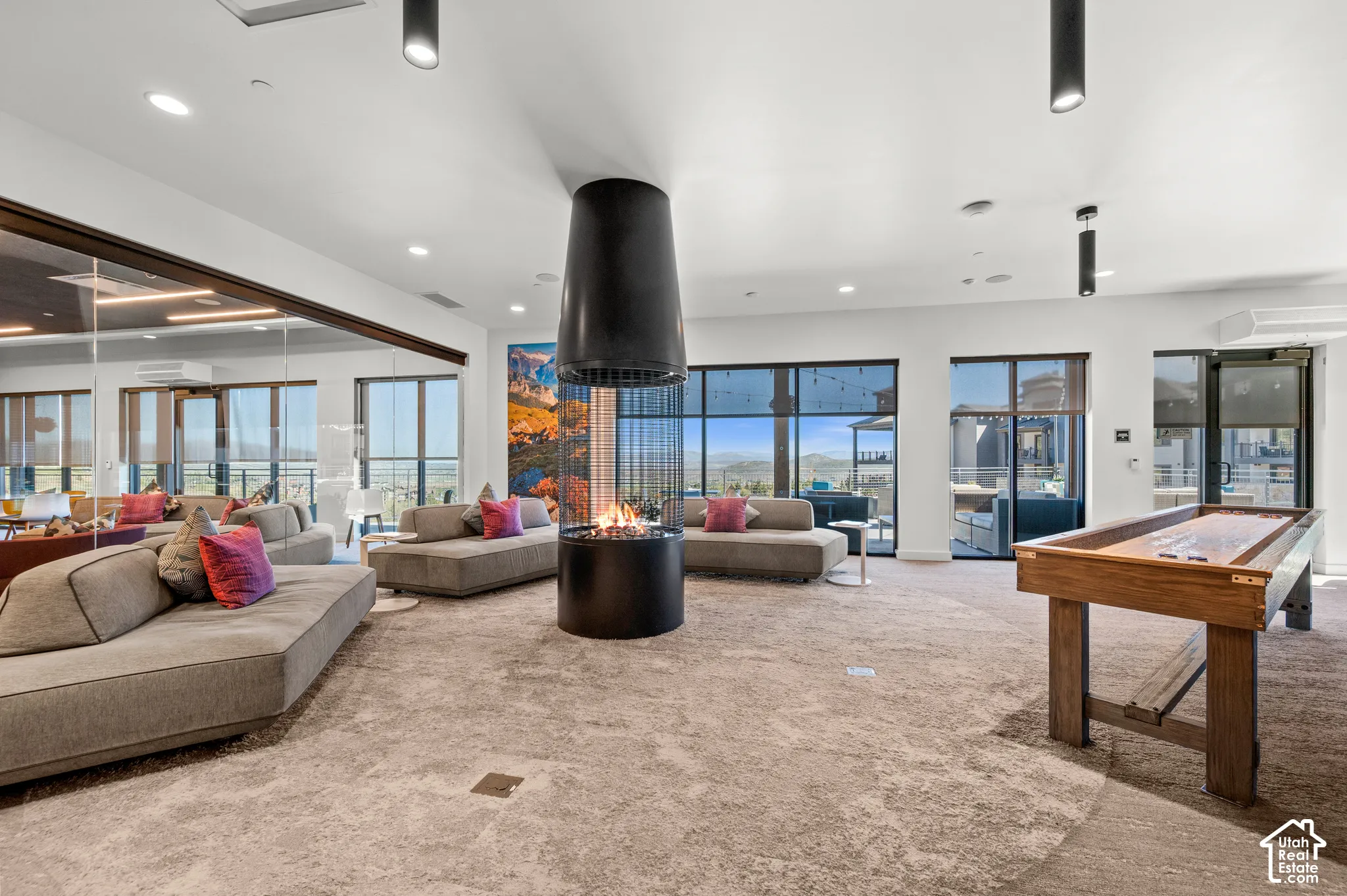 Open-concept common area featuring a suspended fireplace, expansive window walls, recessed lighting, and durable carpet flooring