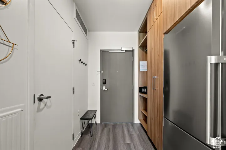 Wood-finish flooring, full-height wood-finish cabinetry, and a large stainless-steel refrigerator